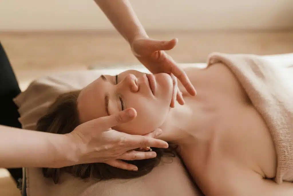 Femme allongé sur une table de massage, les yeux fermés, se faisant masser le crâne après avoir tapé massage crânien angers sur Google et découvert Soléo Massage.