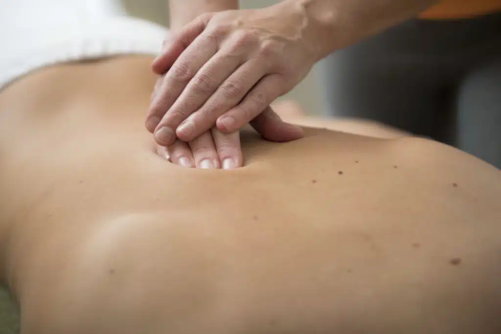 Une personne allongée sur une table de massage, se faisant masser de façon appuyée lors d'un massage deep tissue angers.